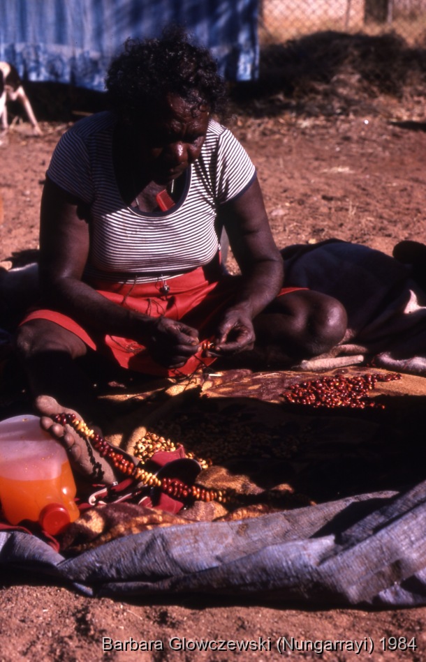 Fieldwork, Lajamanu 1984 /  Pampirriya Nungarrayi making necklace from yinirnti beans  / Barbara Glowczewski / Lajamanu, Tanami Desert, Central Australia, NT